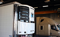 A newly installed trailer refrigeration ("reefer") unit; truck in back is in the middle of an APU (TriPac) installation.