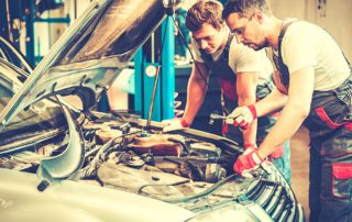 two young mechanics working on a car