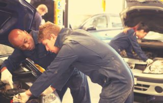 Technicians working on cars in a shop