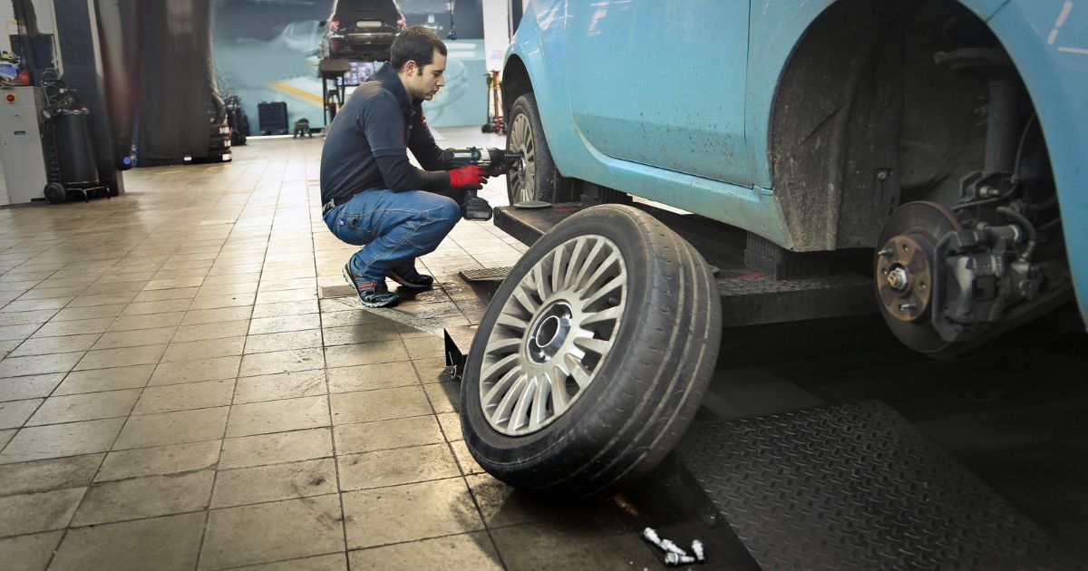 Technician changing tires on a car in a shop