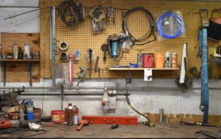 A wall of an automotive repair shop with different tools and equipment hanging up