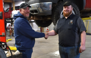Shop Owner and technician shaking hands in a shop