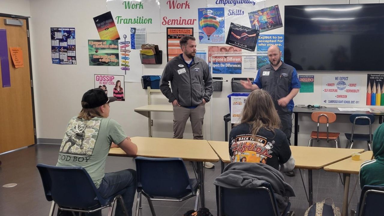 Ford employees talking in front of auto students